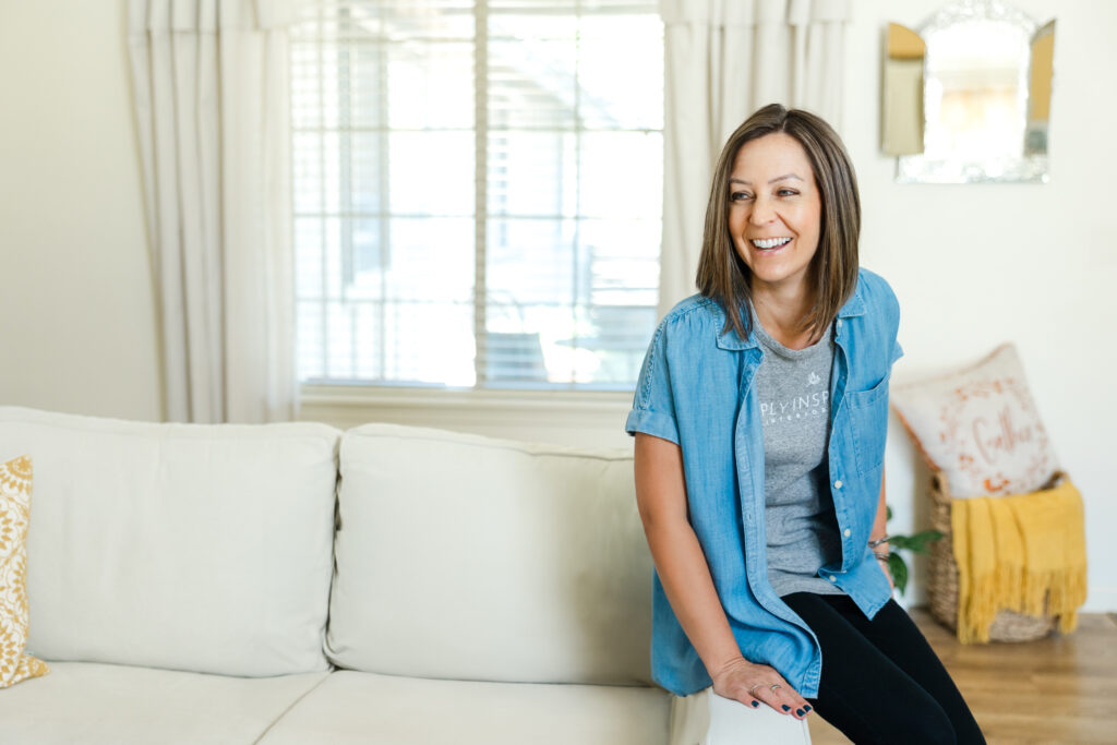 Home organizer and Simply Inspired Interiors founder smiling on a cozy sofa during branding photoshoot.