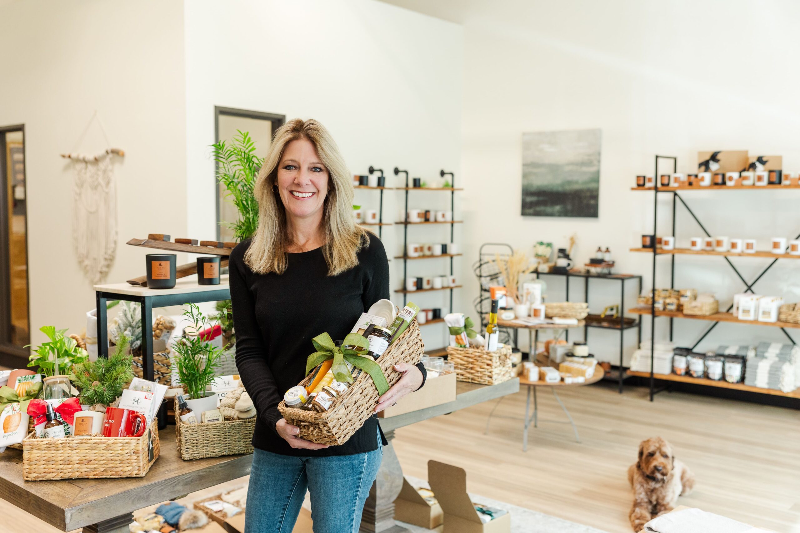 Pelican Place founder holding a beautifully curated basket, surrounded by products in her shop.