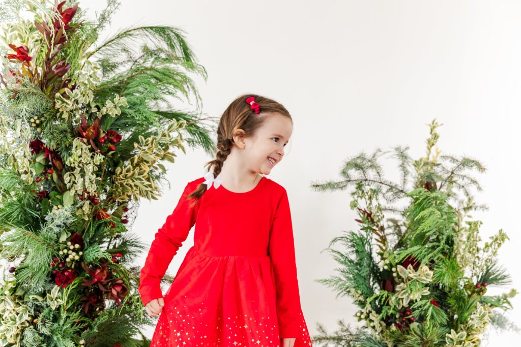 Family-friendly holiday greenery session capturing genuine expressions of a kid