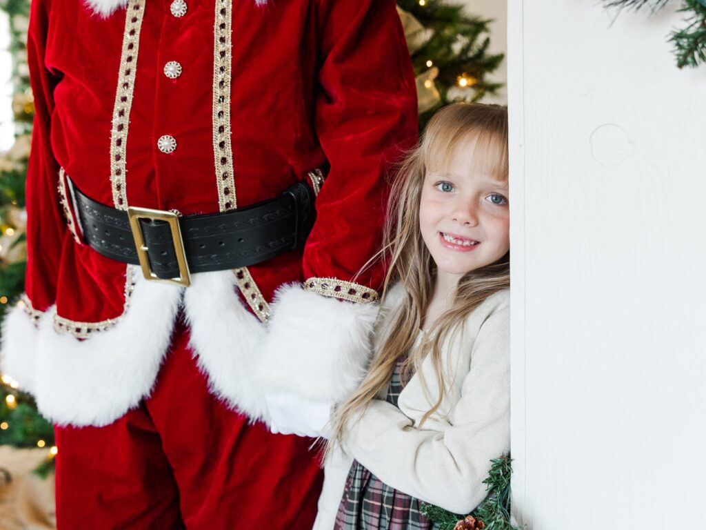 Child holding Santa’s hand during a holiday portrait session