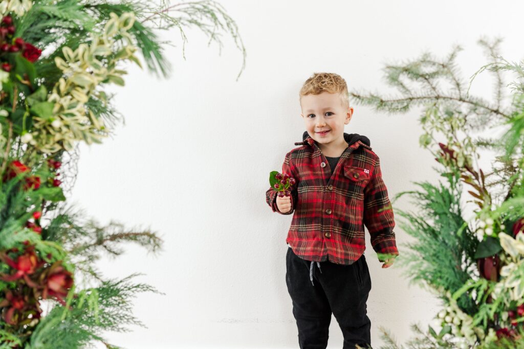 A cute little boy in a Holiday Greenery background