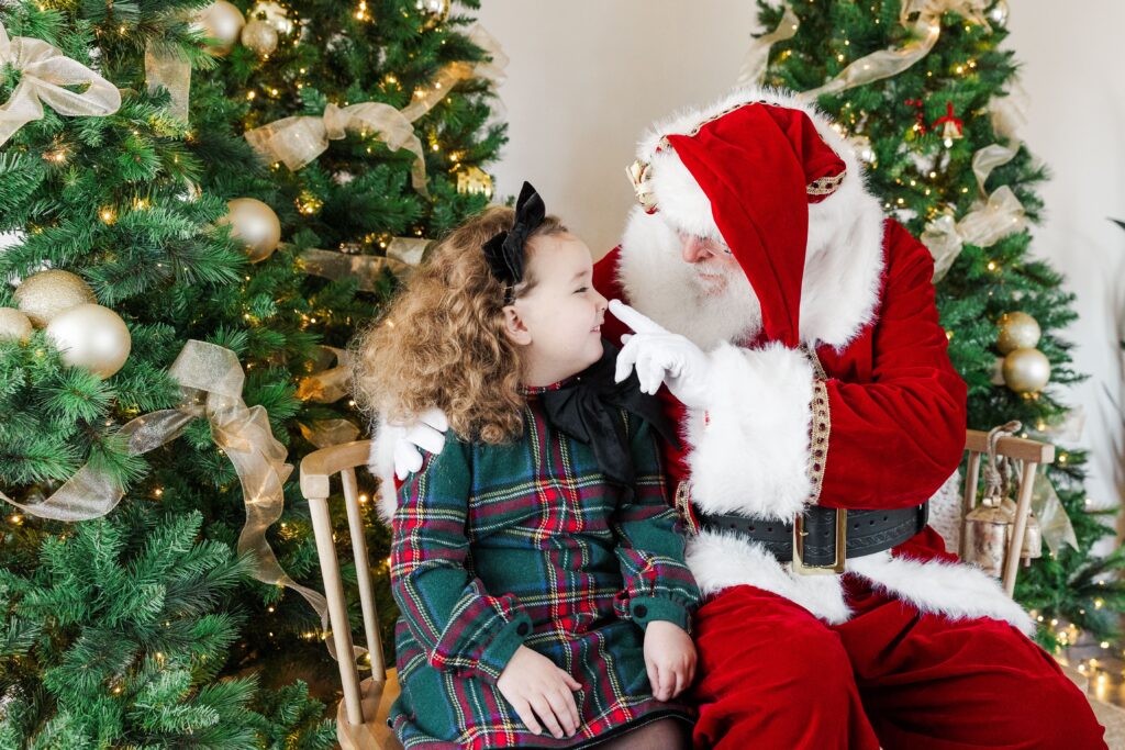 Little one sharing holiday wishes with Santa during a photo session.