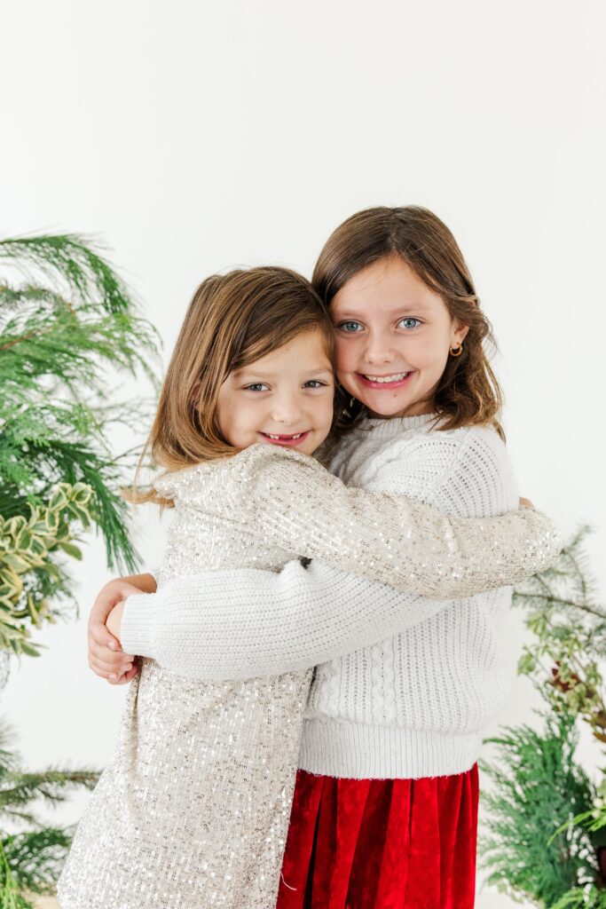Kids standing in soft holiday greenery setup for seasonal portraits