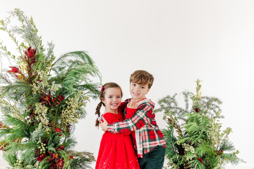 Little ones posing in front of a botanical festive greenery setup