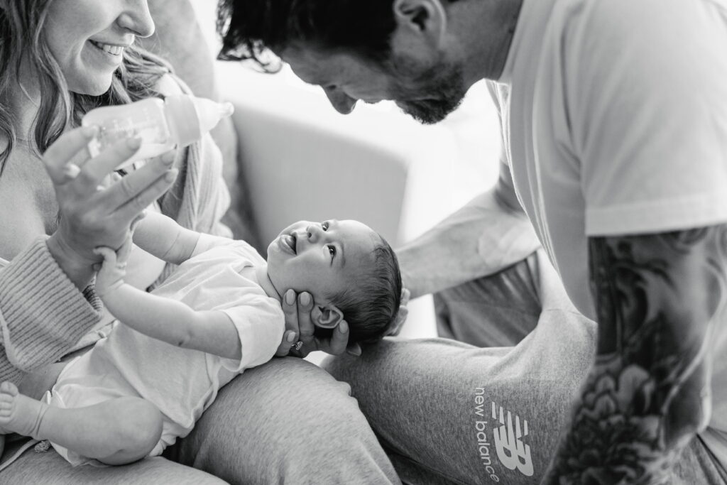 Parents cuddling their newborn together during a relaxed in‑home session.