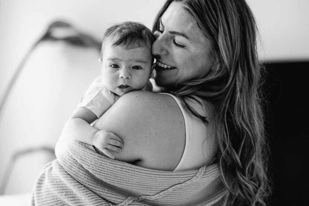 Lindsey carrying her baby through a bright, airy living room.
