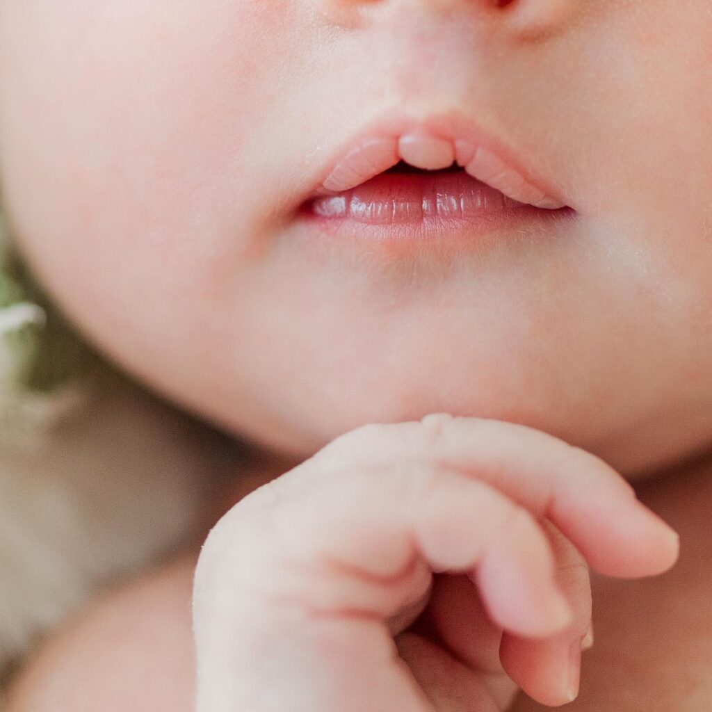 Close-up of newborn baby’s tiny fingers curled