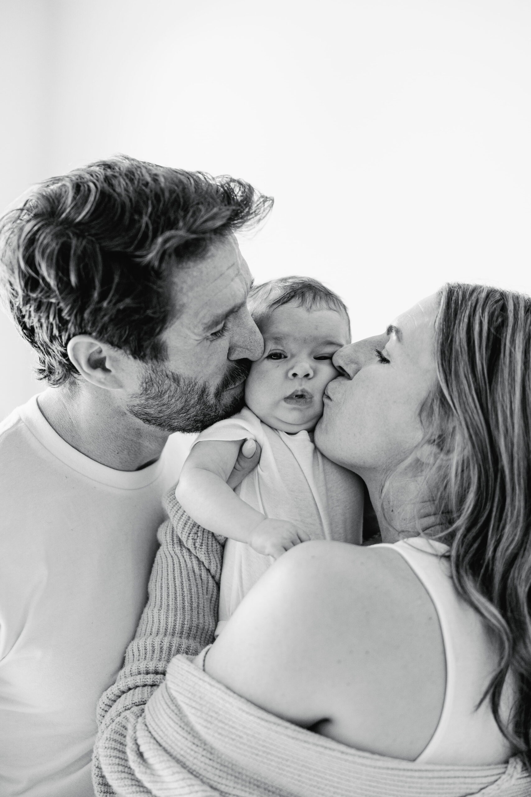 Parents sharing a tender moment with their newborn in their home.
