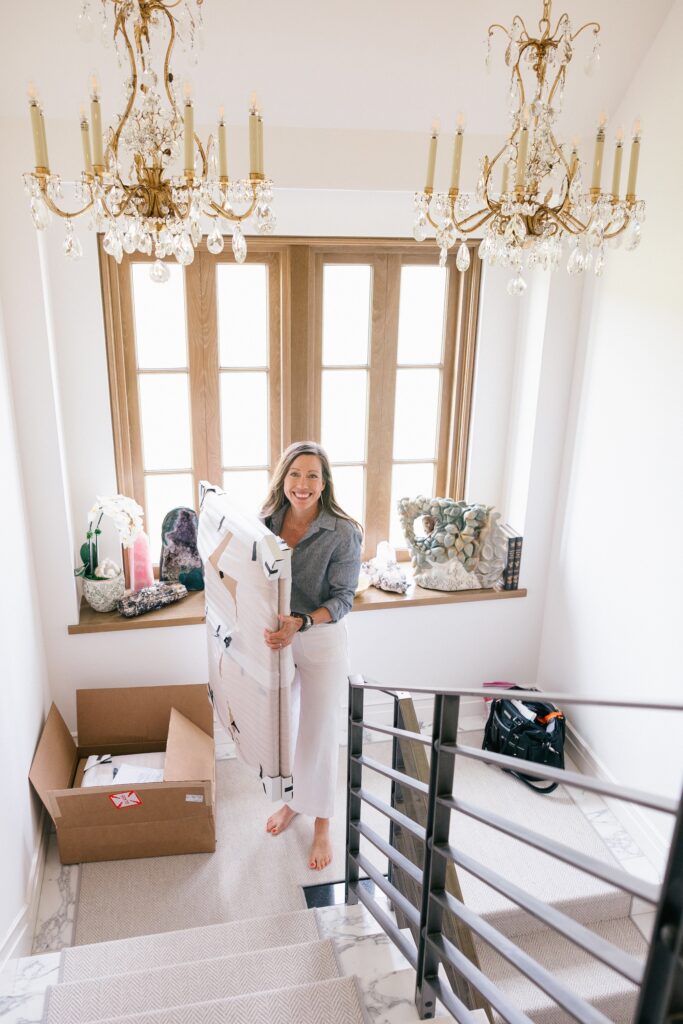 Photographer carrying framed portraits up staircase for custom wall art installation