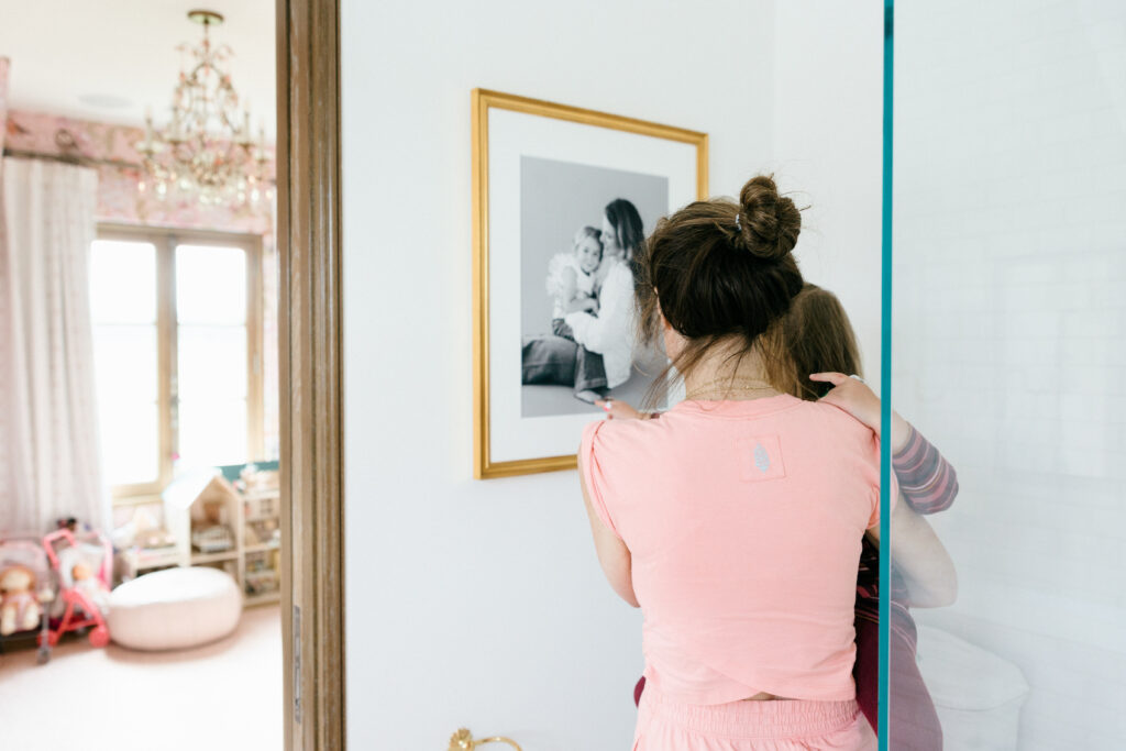 Mother and daughter looking at framed portrait in bathroom