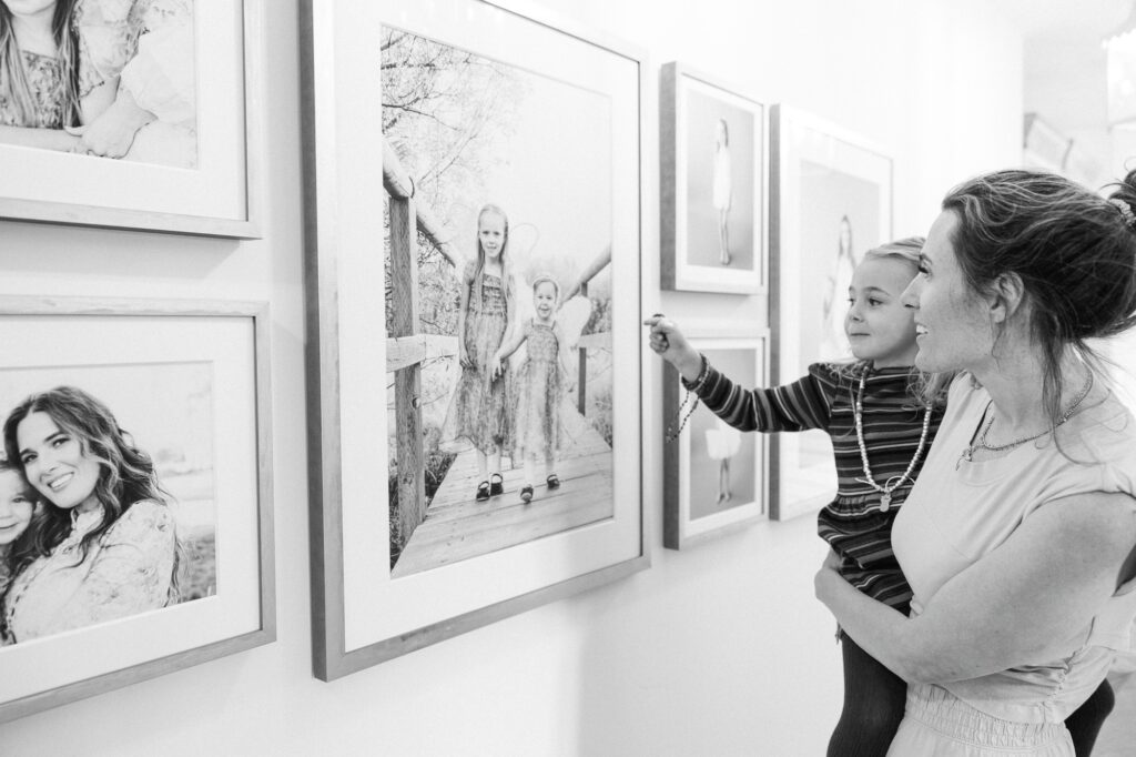 Mother and daughter pointing at portraits in hallway gallery wall