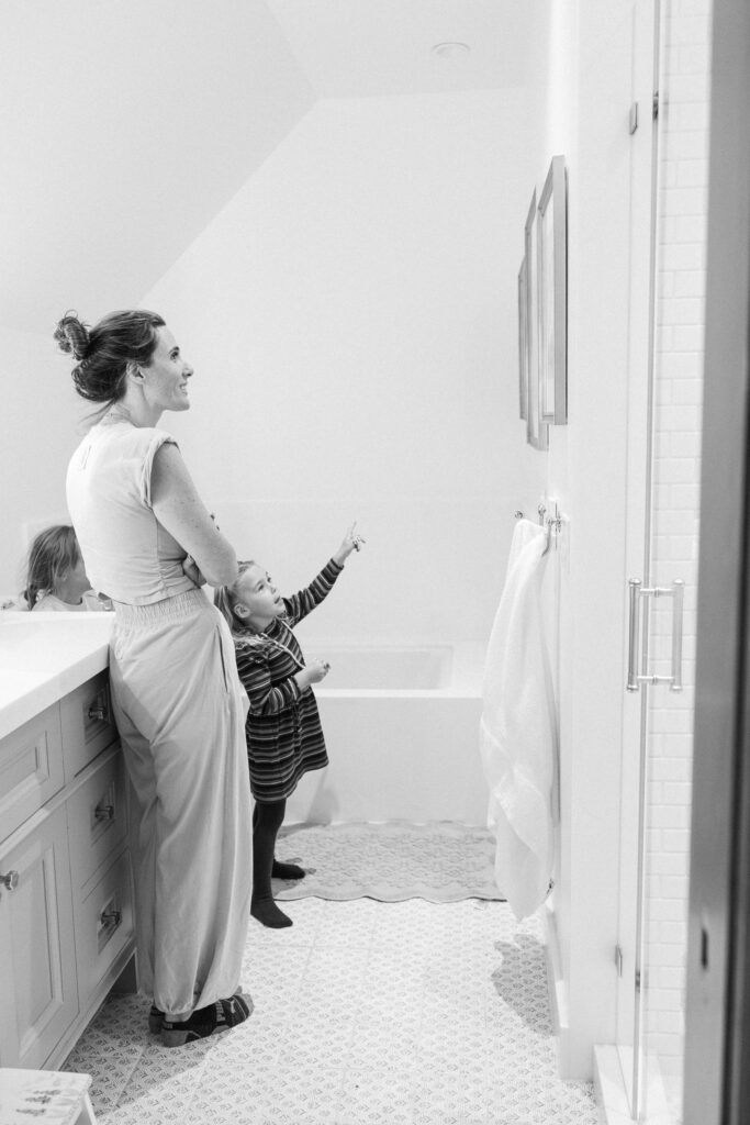 Little girl reaching up toward her mother daughter portrait in bathroom