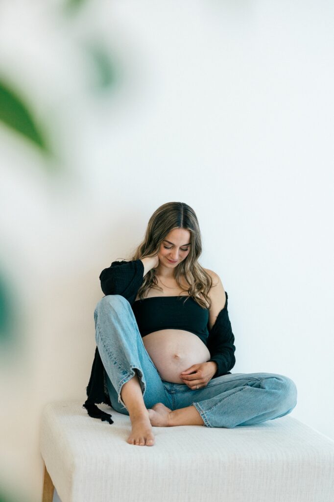Expecting mother holding her baby bump in a bright studio